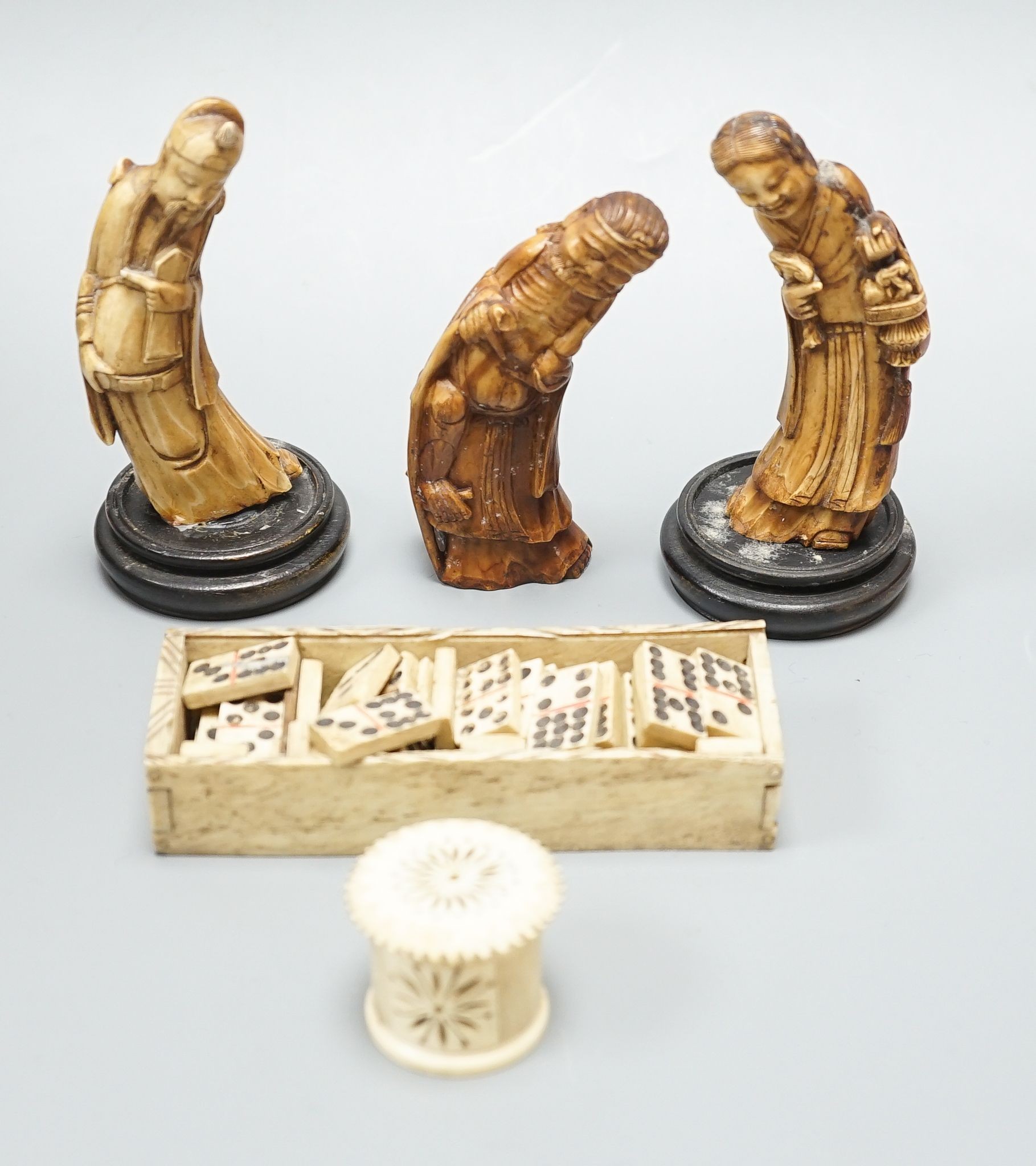 Three Chinese carved hippo tooth figures of Immortals, a 19th-century bone boxed dominoes set and a 19th-century ivory case set of dominoes